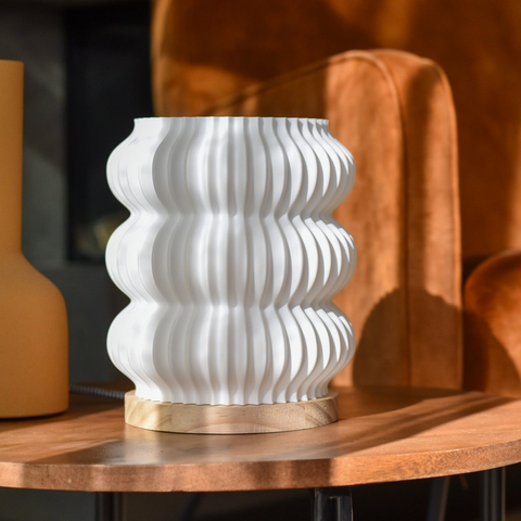 Drei skandinavisch inspirierte Tischlampen in unterschiedlichen Formen, aus Bioplastik und Naturholz, stilvoll arrangiert auf einem Sideboard in modernem Interieur.