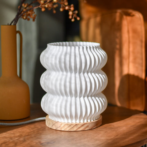 Tischlampe Bolla aus Naturholz und Bioplastik auf einem Sideboard in modernem Wohnambiente, weiches Licht im Raum